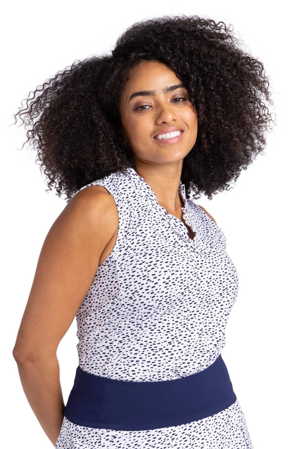 Front view of a woman wearing a sleeveless top with a v-neckline framed with small ruffle trim. The top is in the Rain Delay print - a navy blue spotted pattern on a white background.