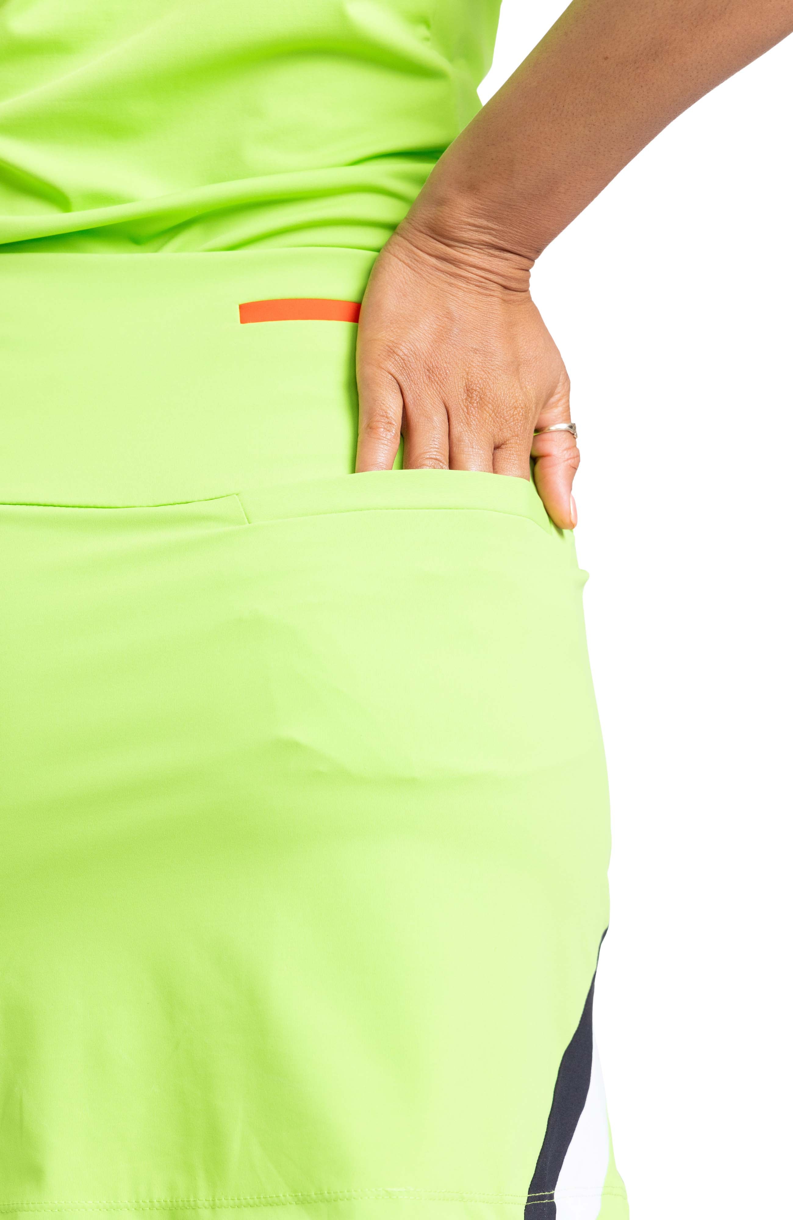 Back detail view of a woman wearing a green skort with her hand in the back right pocket.